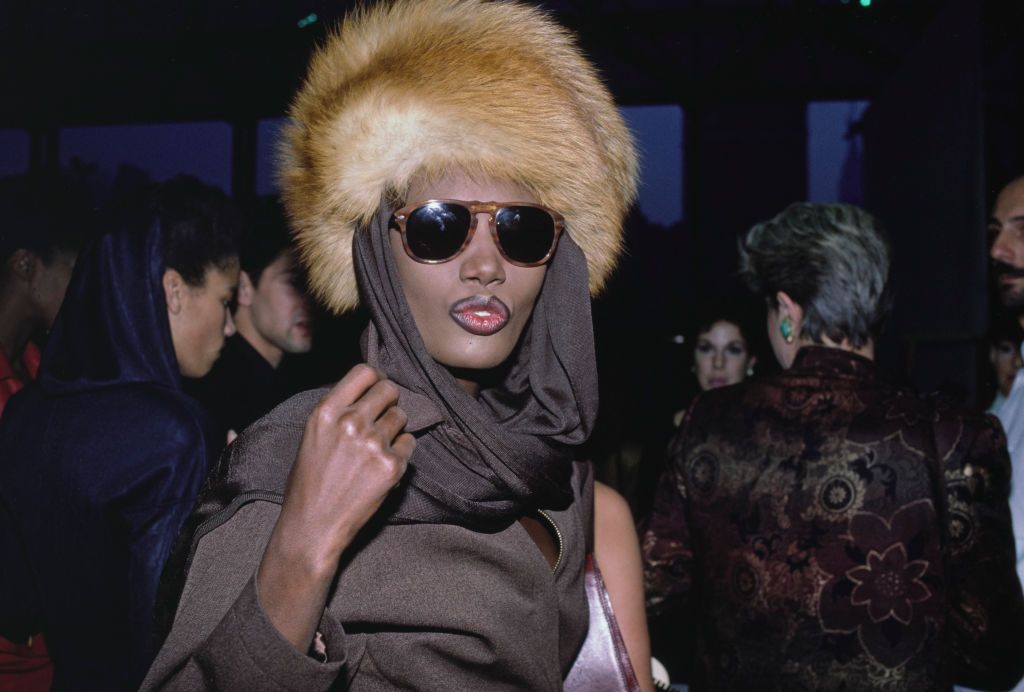 <p>Attending The World’s Largest Photo Session Benefit for AIDS Research Foundation in New York in 1986. Her incredible outfit includes a fur hat with a brown scarf and shades.</p>