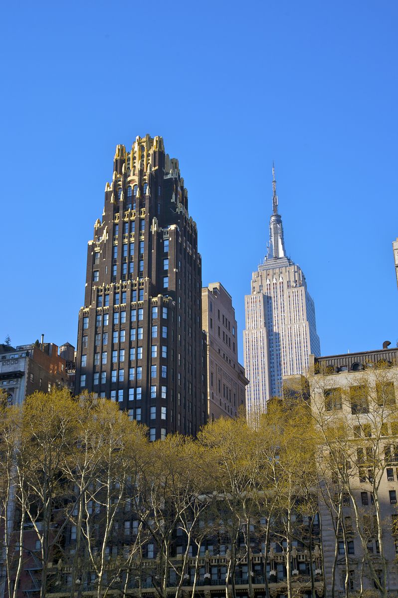 <p>Formerly the American Radiator Building, this stunning New York city building was converted to the <a href="https://bryantparkhotel.com/about/">Bryant Park Hotel</a> in 2001. </p><p>Built in 1924 by architects Raymond Hood and John Mead Howells, the design—with its black brick and elaborate, gold-colored masonry top—was considered Neo-Gothic but with ornamentation that made it lean more toward the Art Deco. Here, it's shown with the Empire State Building in the background.</p>