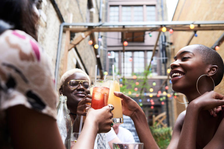 group of Black women friends toasting with cheers and happy