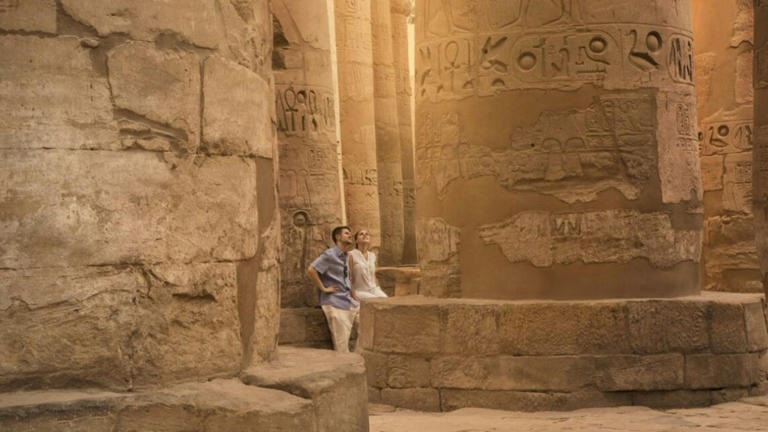 A couple peruses giant columns in Egypt.