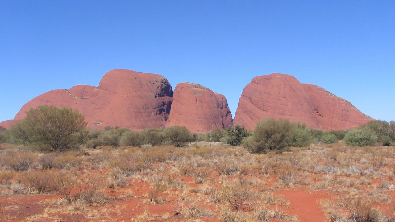 <p>European explorers called this area the Olgas. Explore the unique domed formations of Kata Tjuta, each holding its ancient significance in Aboriginal culture. Kata Tjuta, meaning ‘many heads,’ is sacred to the Aboriginal Anangu people who have lived there for over 22,000 years. It holds great spiritual significance, forming a vital part of their cultural heritage. Visitors can explore this sacred site through cultural tours, gaining insights into the region’s profound history and Dreamtime stories.</p>