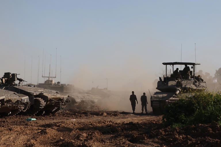 Israel soldiers walk beside their military vehicles near the order with Gaza on March 10. According to the IDF, only the members of two divisions remain in the strip, down from five during the war's peak.
