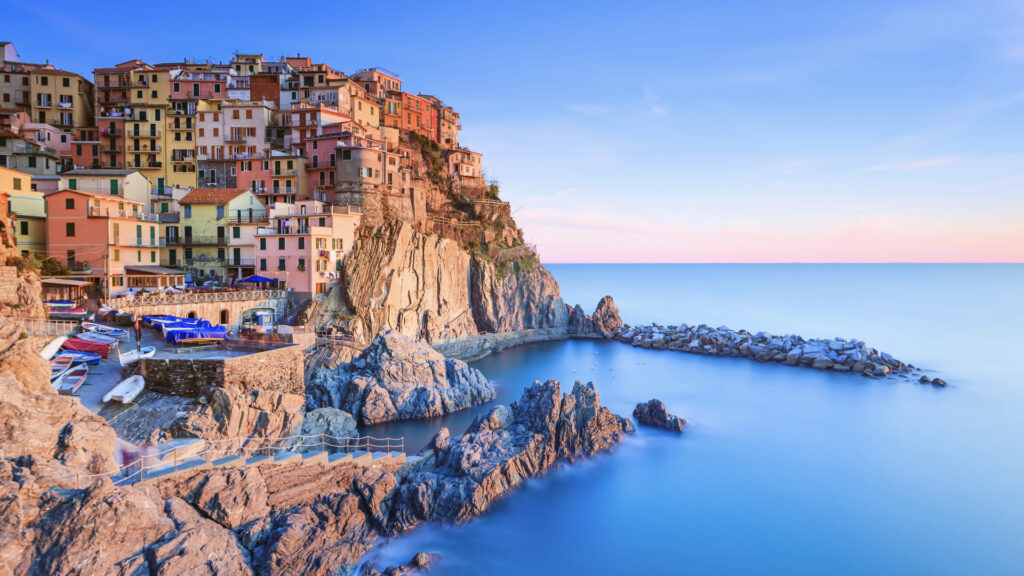 <p>Cinque Terre, known as “The Five Lands,” has stunning coastal sunsets and comprises five charming fishing villages: Monterosso al Mare, Vernazza, Corniglia, Manarola, and Riomaggiore. Connected by scenic narrow roads and a railway, it offers a remote yet beautiful escape. </p><p>To explore, opt for hiking between villages, requiring a Cinque Terre Trekking Card for access. Alternatively, the Cinque Terre Train Card grants unlimited train travel and hiking path entry. Ideal for group travel, this Italian gem promises unforgettable experiences amidst picturesque landscapes and traditional seaside charm.</p>