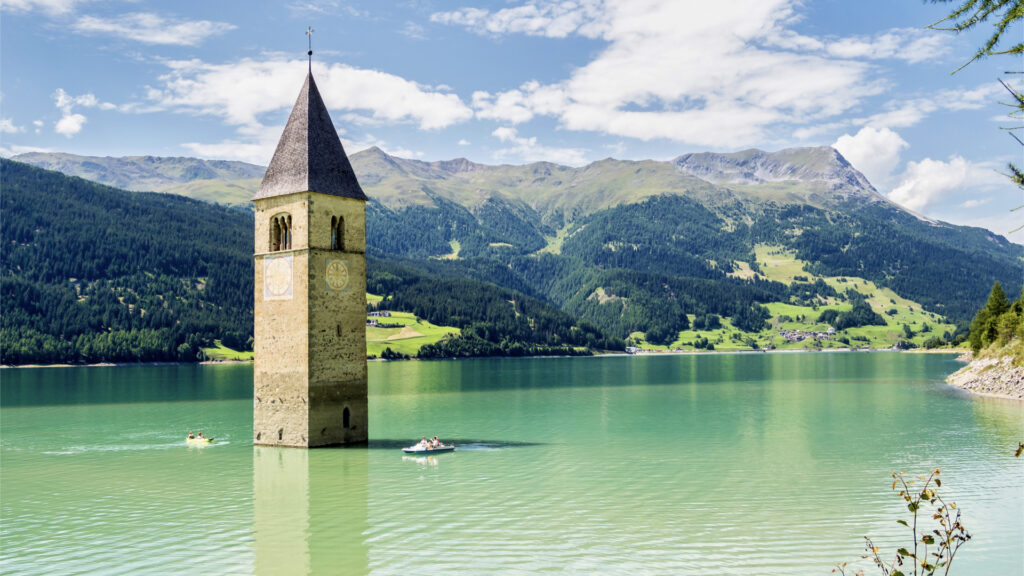 <p>Lake Resia, situated in South Tyrol’s Alpine region, stands out as a unique destination in Italy. Its eerie beauty evokes a scene from a Stephen King novel, with a submerged church steeple rising from its icy waters. Once part of the drowned village of Curon, Lake Resia has inspired literature and a Netflix series. </p><p>While popular with hikers in summer, it offers a surreal experience in winter, allowing visitors to walk across its frozen surface. With its haunting allure and fascinating history, Lake Resia promises an unforgettable adventure for those seeking something extraordinary in Italy.</p>