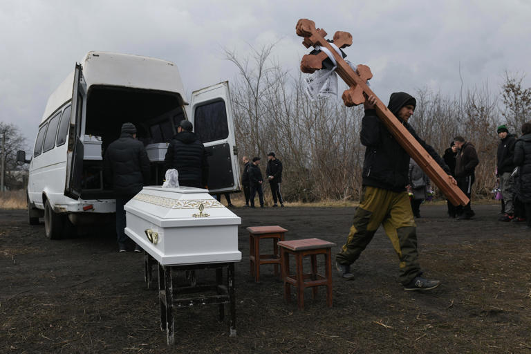 TOPSHOT - EDITORS NOTE: Graphic content / A man carries wooden crosses during a funeral ceremony of three children, killed in what local Moscow-installed officials say was a Ukrainian attack, in Donetsk, Russian-controlled Ukraine, on March 17, 2024, amid ongoing Russian-Ukrainian conflict. (Photo by STRINGER / AFP) (Photo by STRINGER/AFP via Getty Images) ORIG FILE ID: 2084801722