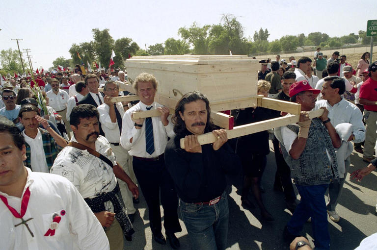 Robert F. Kennedy Jr., brings up the rear as he joins Edward James Olmos, front, then-Rep. Joseph P. Kennedy II and others in carrying Cesar Chavez's casket in 1993. Many people helped carry it in a miles-long funeral procession as Chavez's family grew tired. ((Bob Galbraith / Associated Press))