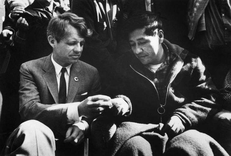 Sen. Robert F. Kennedy, left, breaks bread with Cesar Chavez in Delano, Calif., in 1968 as Chavez ends a 25-day fast in support of nonviolence in the strike against grape producers. ((Bettmann Archive))