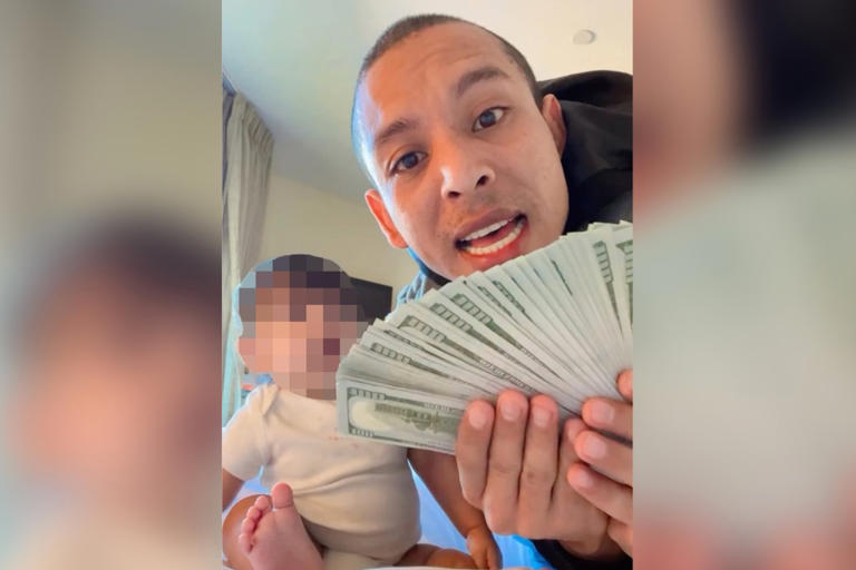 Leonel Moreno holds up a wad of cash while sitting next to his baby Leonel Moreno/Instagram