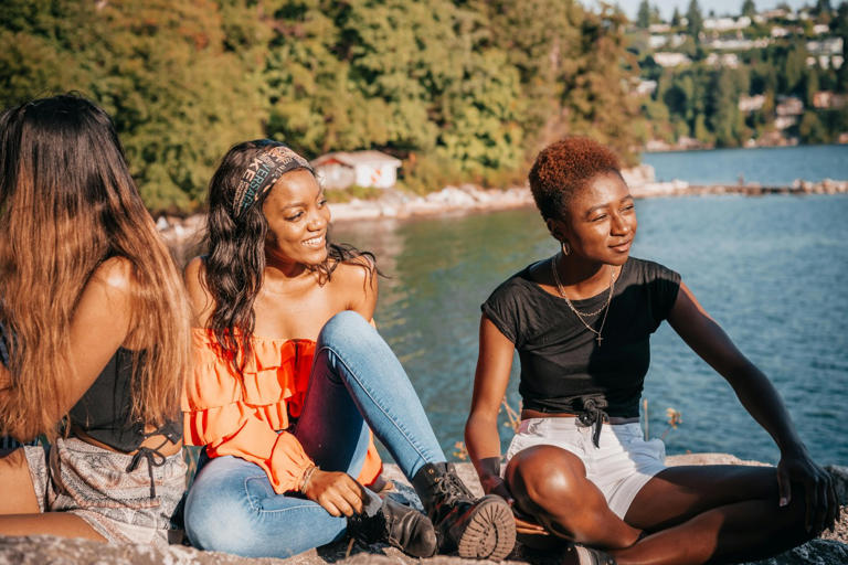 women sitting around talking near a river