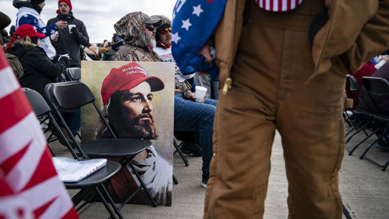 An attendee walks past a poster of Jesus wearing a "Make America Great Again" hat at a campaign rally for then-President Donald Trump in Avoca, Pennsylvania, on November 2, 2020. - Al Drago/Bloomberg/Getty Images