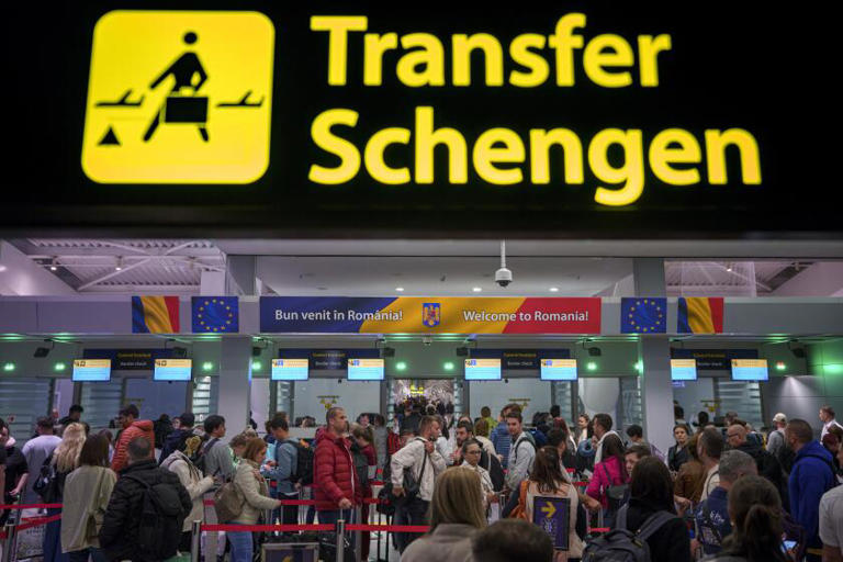 Passengers arriving at the Henri Coanda International Airport pass under a Schengen Information sign, in Otopeni, near Bucharest, Romania, on Sunday. Romania and Bulgaria joined Europe's passport- and visa-free Schengen Area, applying only to travelers arriving by air and sea. ((Andreea Alexandru / Associated Press))