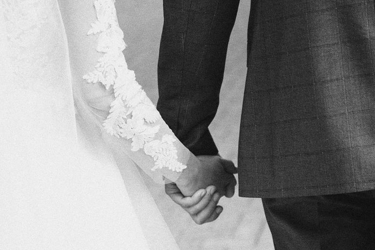 The bride and groom hold hands.