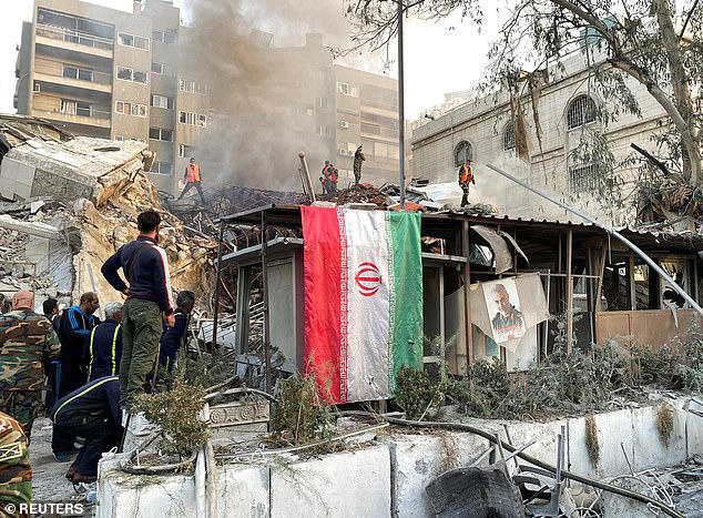 An Iranian flag is seen hanging over the bombed out building, which was flattened in the strike