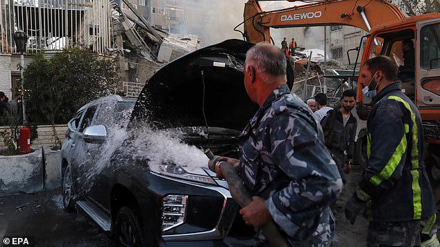 A damaged vehicle is doused following an airstrike next to the Iranian consulate in Damascus, Syria on Monday, April 1, 2024