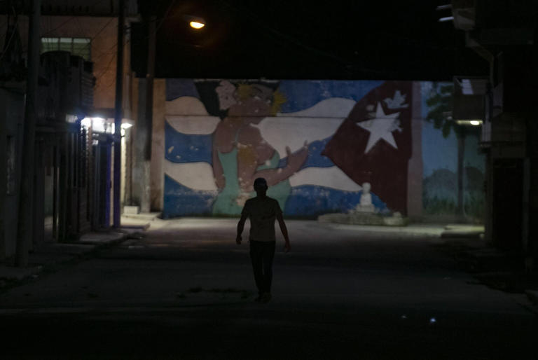 A pedestrian walked down a street during a rolling blackout in Havana on March 26.