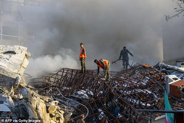 The strike on the Iranian consulate building killed as many as seven people, an Iranian Ambassador has claimed. Emergency personnel are pictured today extinguishing a fire at the site of strikes which hit a building next to the Iranian embassy