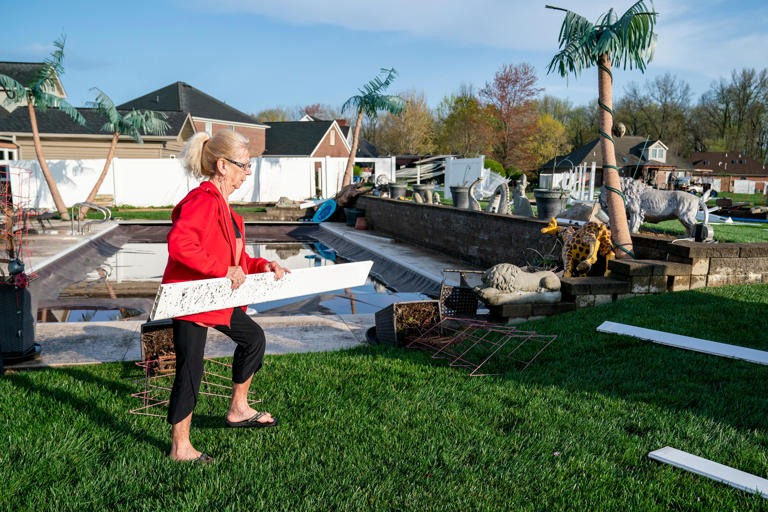 Lois Schmitt picks up a piece of fence in her yard after strong storm came through causing damage around her home Tuesday morning, April 2, 2024.