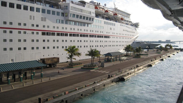 A cruise ship is docked at a pier. Carnival lead DBK