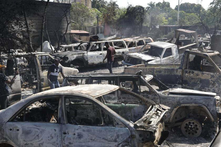 People look for salvageable pieces from burned cars at a mechanic shop that was set on fire during violence by armed gangs in Port-au-Prince, Haiti, on March 25, 2024. ((Odelyn Joseph / Associated Press))