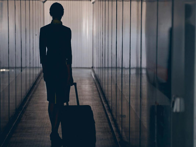 A flight attendant walks down an airplane boarding tunnel. In the latest incident involving crew members from Pakistan International Airlines, a crew member was arrested carrying multiple passports.