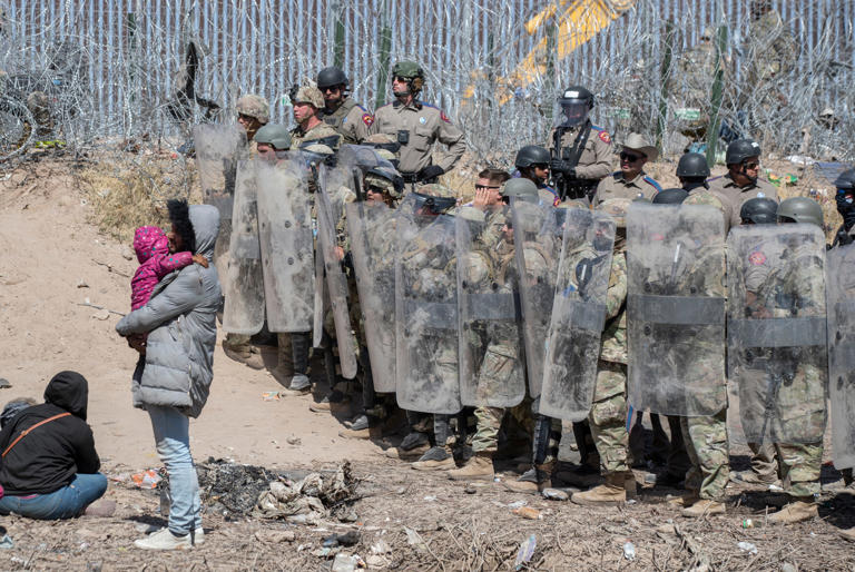 Texas National Guard soldiers and Texas Department of Public Safety troopers use anti-riot gear to prevent asylum-seekers from entering farther into U.S. territory after the migrants crossed the Rio Grande into El Paso on March 22.