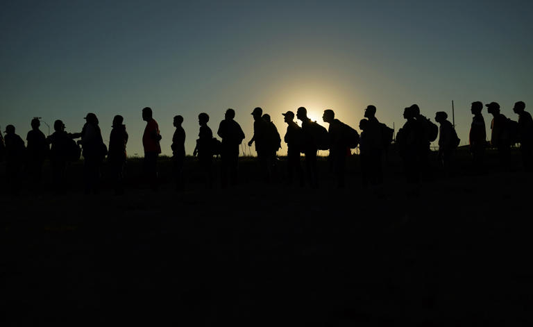Migrants who crossed the Rio Grande and entered the United States from Mexico are lined up for processing by U.S. Customs and Border Protection in Eagle Pass, Texas in September 2023. (Eric Gay/AP)