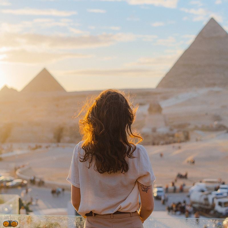 Young Woman Watching The sunset Over The Pyramids Of Giza, Cairo, Egypt, North Africa