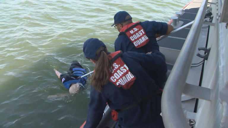 Two members of the U.S Coast Guard in St. Pete practice pulling in someone stranded at sea, using a doll.