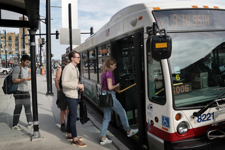 Commuters line up and board a CTA bus near Belmont in Chicago, on Oct. 4, 2023.