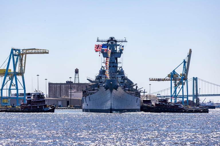 The USS New Jersey Battleship seen from the middle of the Delaware River as tugboats help direct and lead the ship away from Camden to the dry dock in Paulsboro.