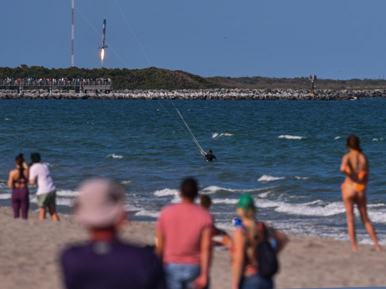 Crowds on the beach in Cape Canaveral watch a SpaceX Falcon 9 booster land March 21 at Canaveral Space Force Station.