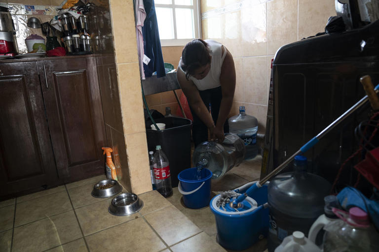 A woman fills a bucket with bottled water at an apartment unit in the Las Peñas neighborhood in Iztapalapa on February 27, 2024 in Mexico City, Mexico. / Credit: TOYA SARNO JORDAN / Getty Images