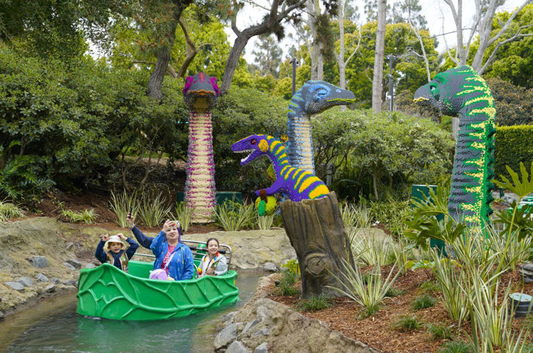 Carlsbad, CA - March 22: At Legoland California on Friday, March 22, 2024 in Carlsbad, CA, a family enjoys the boat ride down Explorer River Quest during the grand opening for Legoland's newest area, Dino Valley.