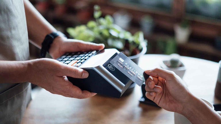 Close up of a woman’s hand paying bill with credit card in a cafe, scanning on a card machine. Electronic payment. Banking and technology