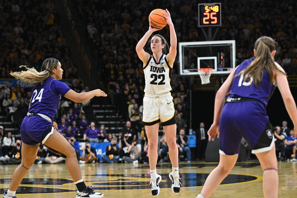 Iowa Hawkeyes guard Caitlin Clark (22) shoots the ball as Holy Cross Crusaders guard Simone Foreman (24) and guard Cara McCormack (15) look on during the fourth quarter of the NCAA first round game at Carver-Hawkeye Arena in Iowa City, IA on March 23, 2024.