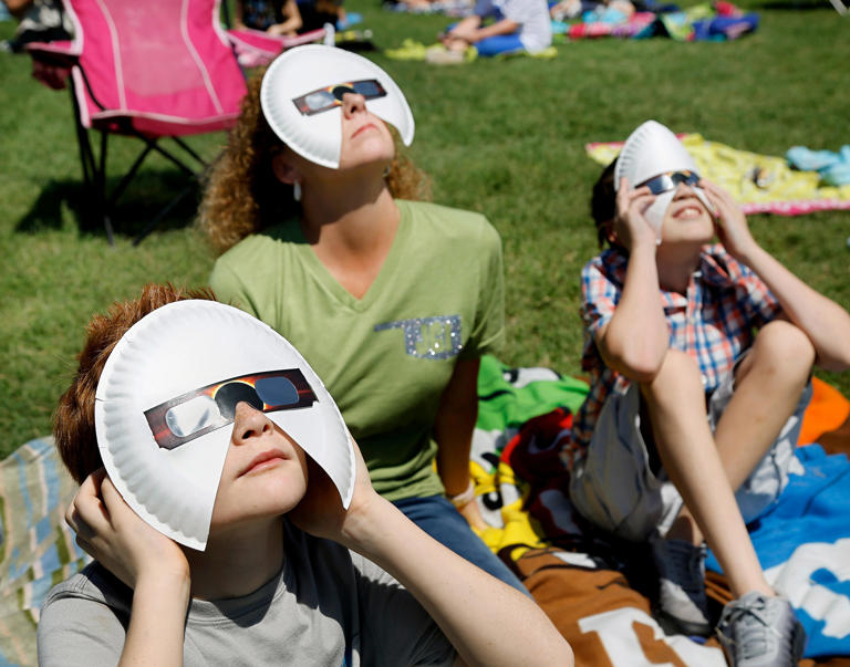 Students Willy Brandt, left, and Paden Eastep, sit with teacher assistant Tassie Burke and use modified viewing glasses to watch the eclipse. The entire student body, faculty and some parents gathered in a field on the north side of James Griffith Intermediate School to view the solar eclipse Monday afternoon, Aug. 21, 2017. Special glasses with very dark lenses were purchased to allow teachers and students to safely view the celestial event. Children were served Moon Pies as a snack to enjoy while viewing the eclipse. Photo by Jim Beckel, The Oklahoman