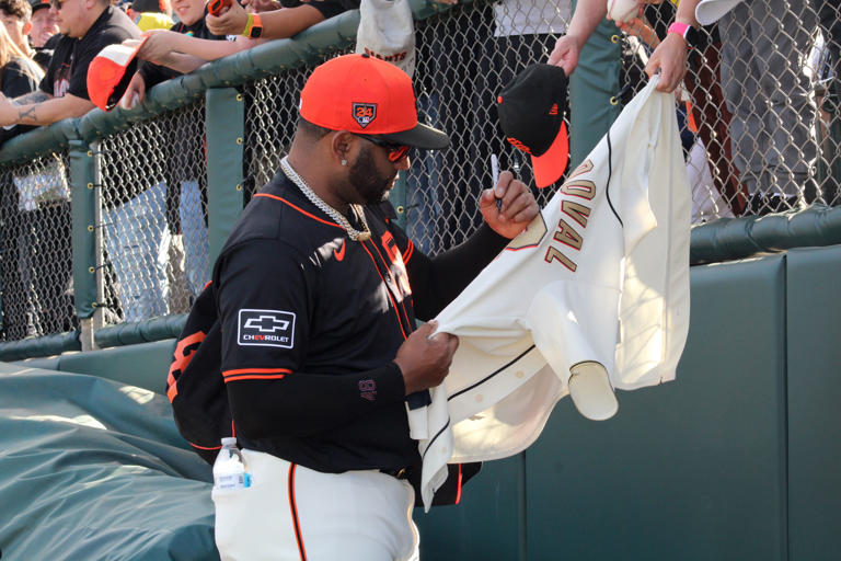 Giants third baseman Pablo Sandoval autographs a jersey before an...