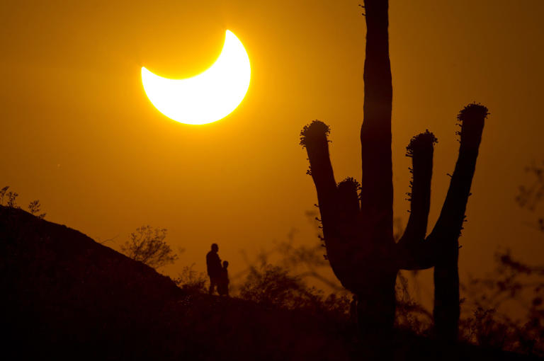 Hikers see a partial solar eclipse over Phoenix in 2012 at Papago Park as the moon's silhouette nipped out a big chunk of the sun's surface area.