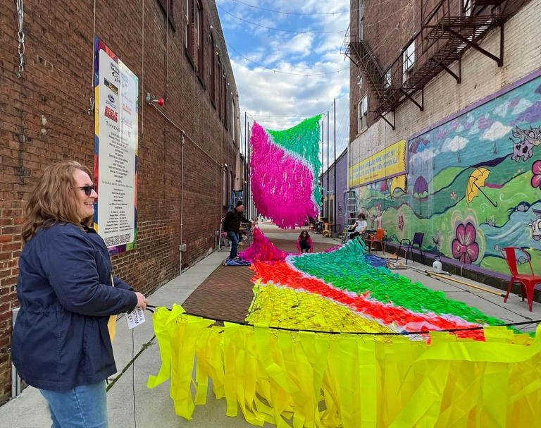 A volunteer helps with the installation of streamers at Umbrella Alley in downtown Louisville. DreamStream features 10,000 colorful streamers, and will be up until mid-May.