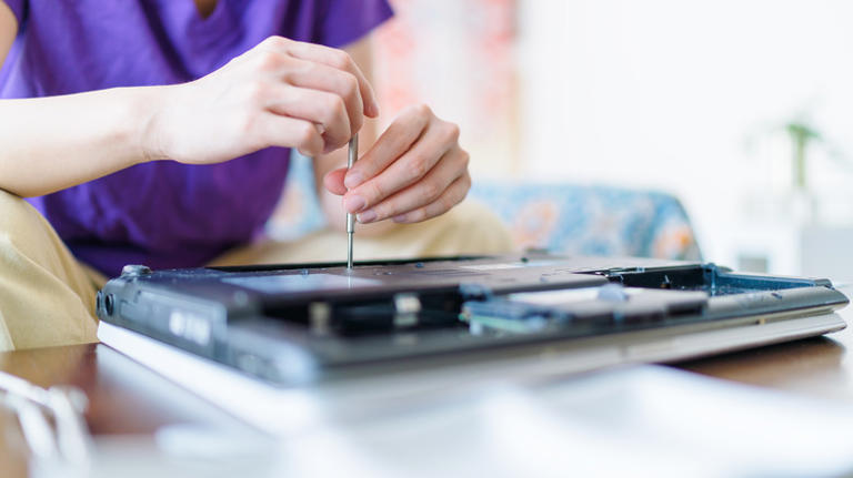 person using a screwdriver on a laptop