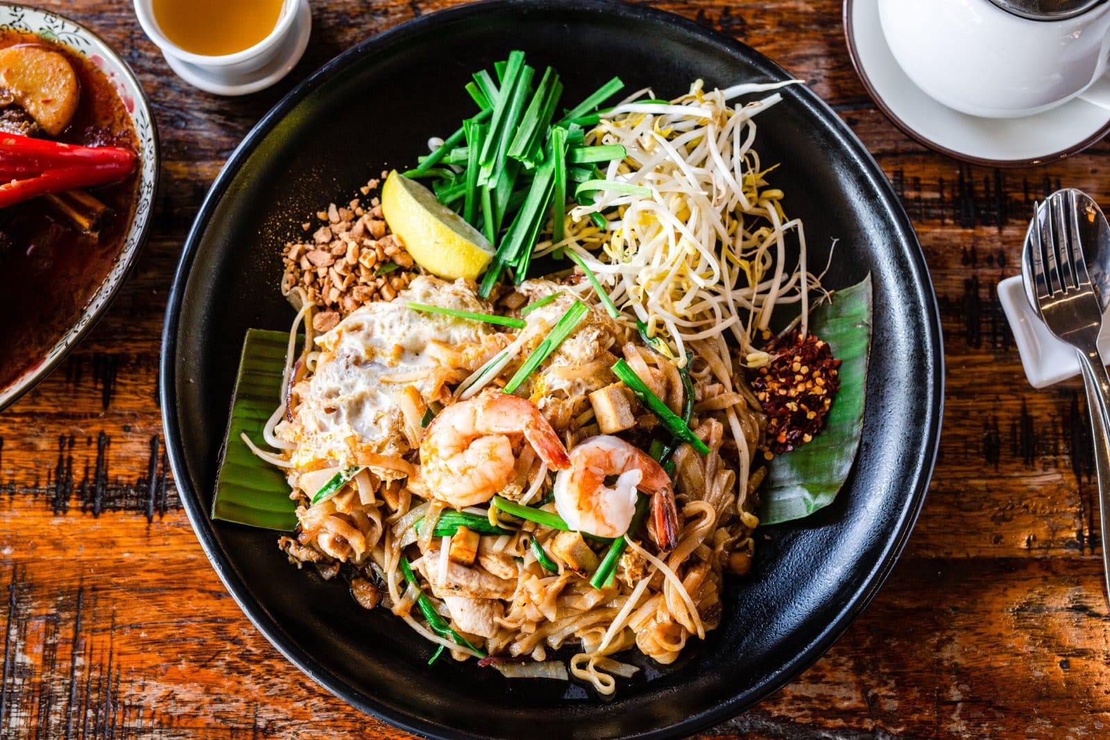 Image Credit: Shutterstock / Giulia M <p>A flavorful stir-fried noodle dish with eggs, tofu, and tamarind sauce, garnished with peanuts, lime, and chili pepper.</p>