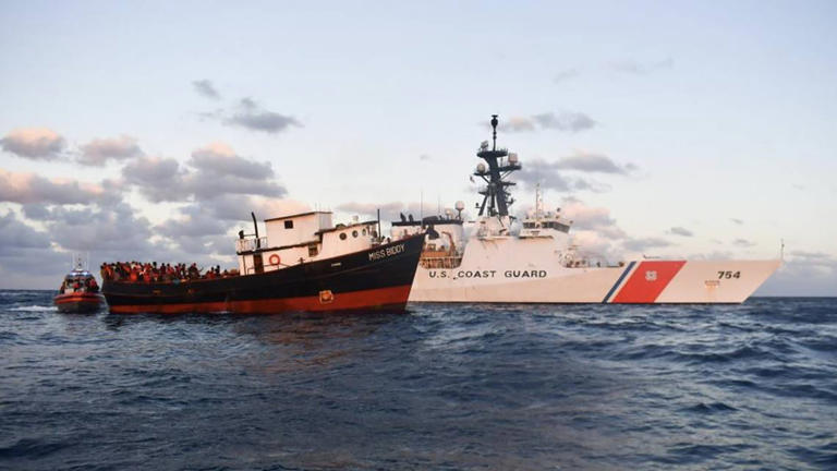 A cargo boat that carried more than 300 people from Haiti floats next to a U.S. Coast Guard cutter off the shore of eastern Cuba on Feb. 15, 2023.