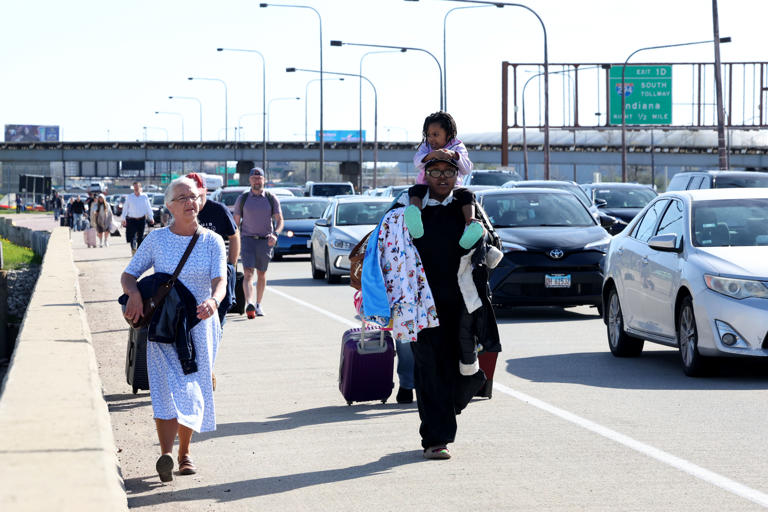 Travelers carry their baggage as they walk toward Terminal 1 at O’Hare International Airport after protesters shut down I-190 heading into the airport on Monday, April 15, 2024, in Chicago.