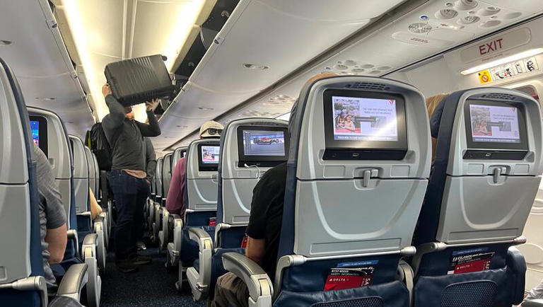 A passenger loads his carry-on suitcase in an overhead compartment on a Delta Air Lines flight at Salt Lake City International Airport, Saturday, March 2, 2024.