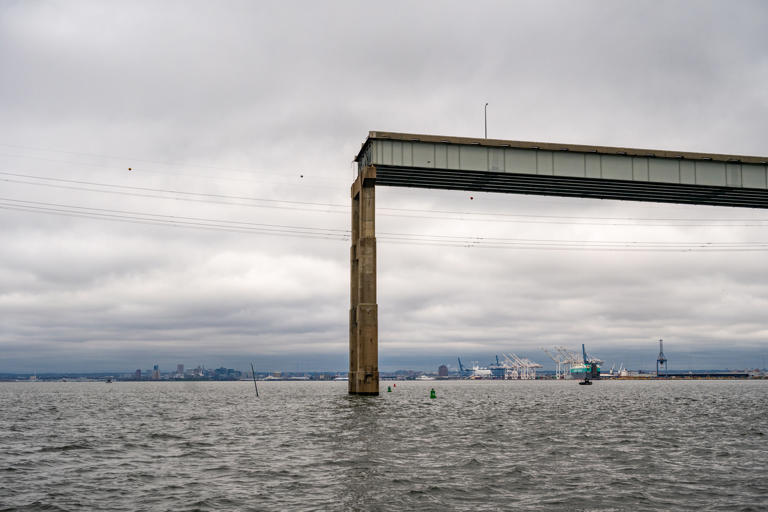 A temporary channel for smaller vessels below a remaining piece of the Francis Scott Key Bridge.