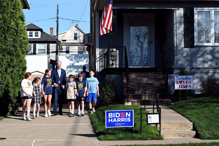 Accompanied by school children, President Joe Biden leaves after a visit to his childhood home in Scranton on Tuesday, on the first stop in his three-day Pennsylvania campaign tour, a week before the primary election.
