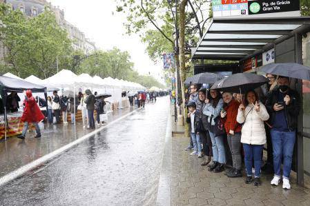 Ciudadanos se resguardan del chaparrón tras desafíar a la lluvia y visitar las casetas de venta de libros en el Paseo de Gràcia en Sant Jordi Toni Albir / EFE