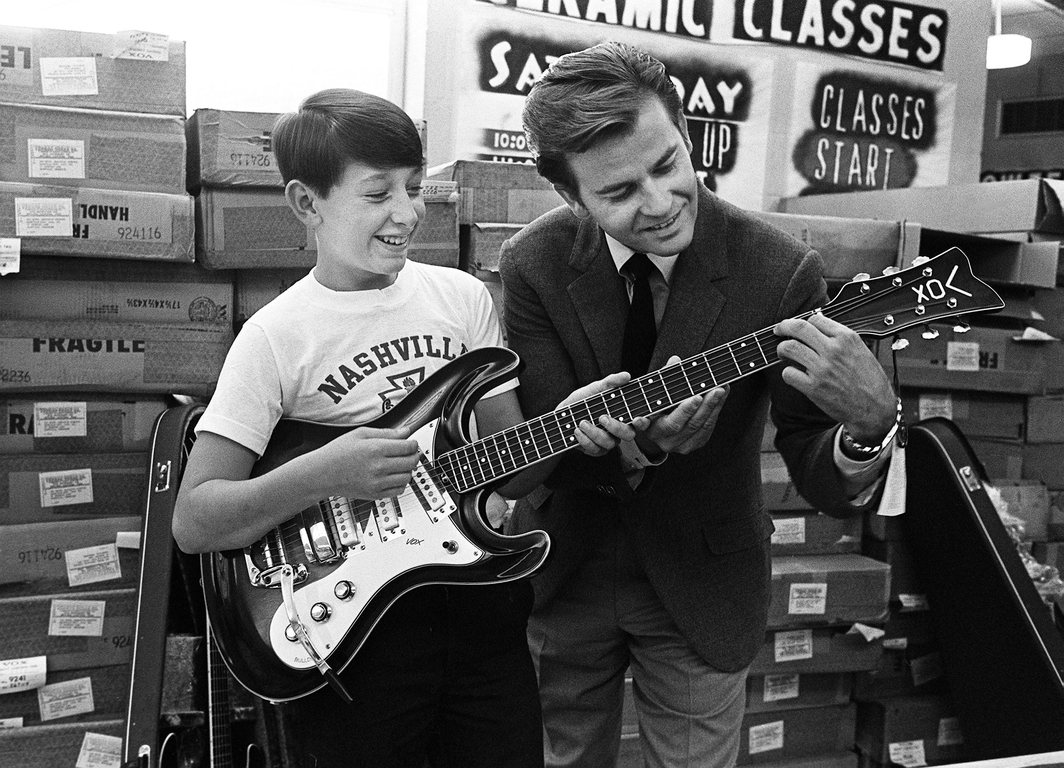 Dick Clark, right, helps out James Hughes, 13, with one of the $1,000 worth of guitars he presented to the Nashville Boy's Club on Thompson Lane Oct. 16, 1968.  68then10 044