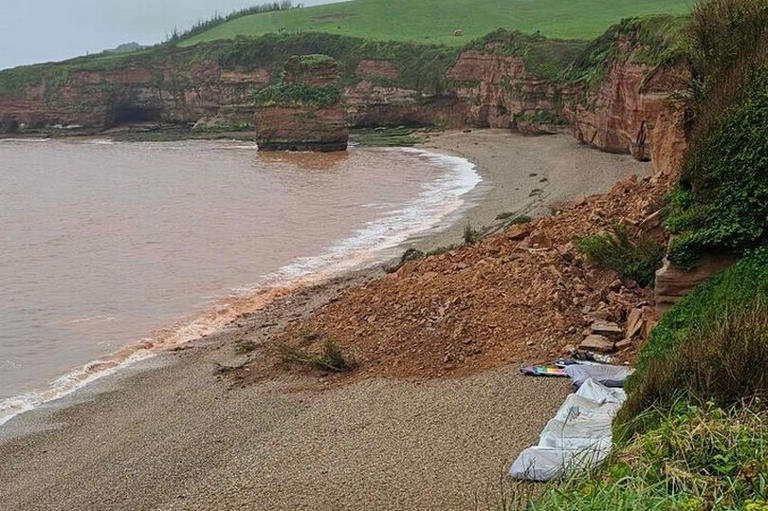 Huge cliff fall sends rocks crashing on to beach, smashing boats and ...