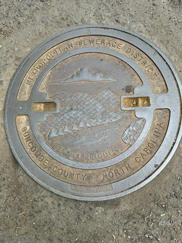 One of the Metropolitan Sewerage District of Buncombe County's current manhole covers is installed in a roadway in its sewer system.
